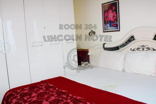 a bedroom with a white bed with a red blanket at Lincoln Prestige Hotel in Accra