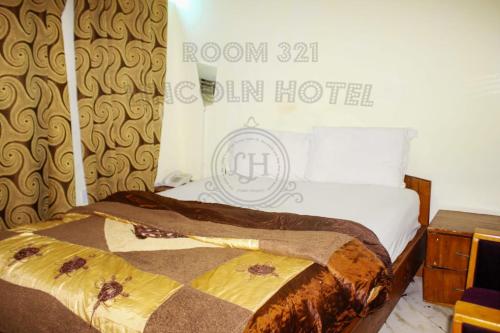a hotel room with a bed with a sign on the wall at Lincoln Prestige Hotel in Accra