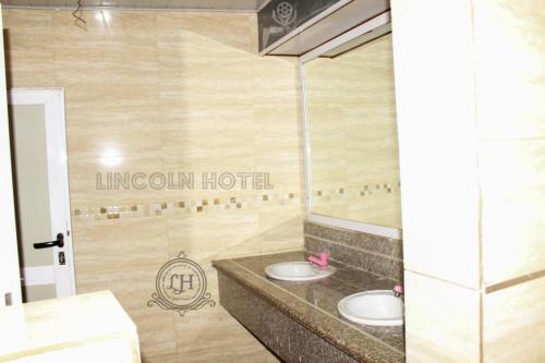 two sinks in a bathroom with a hotel sign on the wall at Lincoln Prestige Hotel in Accra