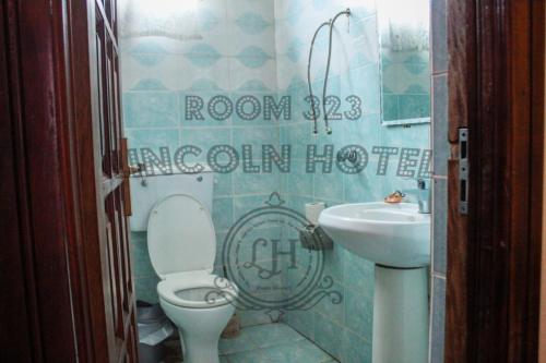 a bathroom with a toilet and a sink at Lincoln Prestige Hotel in Accra