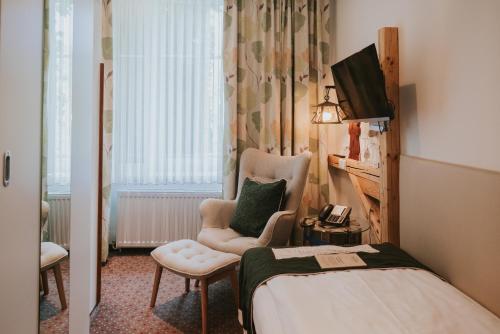 a room with a bed and a chair and a television at Boutiquehotel Stadthalle in Vienna