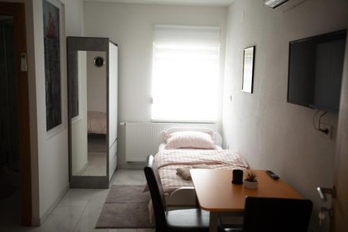 a room with a bed and a table and a window at Apartmani Link in Požega