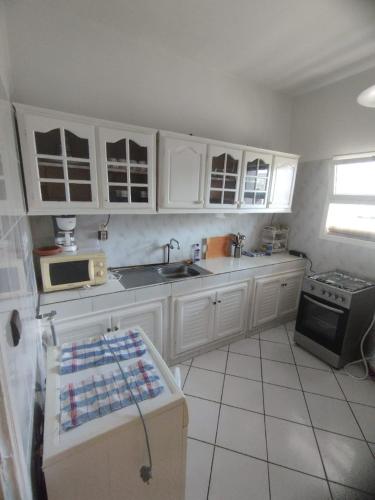 a kitchen with white cabinets and a sink and a stove at Appartement complexe Arrous Bahr mikki beach vue piscine et jardin in Tangier