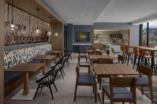 a restaurant with wooden tables and chairs and a bar at Homewood Suites By Hilton Grand Prairie At EpicCentral in Grand Prairie