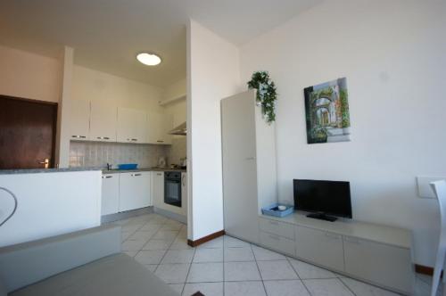 Una cocina con gabinetes blancos y un televisor de pantalla plana. en Manzoni, en Stresa