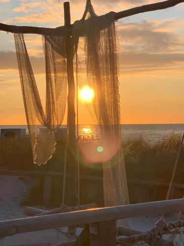 a view of the sunset from the beach with chains at Am Horizont No 1 für 2-4 Pers, 2 Schlafz, Babybett, Südbalkon, kostenloser Parkplatz, 500 Meter zum Strand in Zingst
