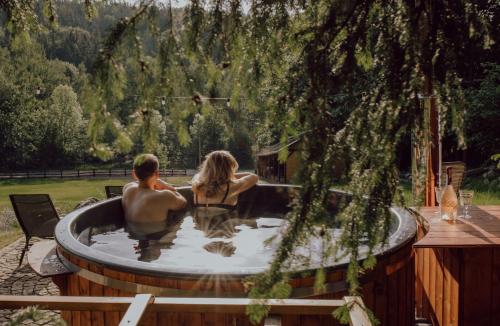 a man and a woman sitting in a hot tub at Zielony Jeleń - sauna i jacuzzi in Szklarska Poręba