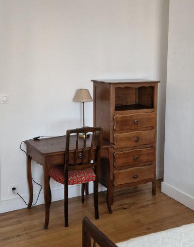 - un bureau en bois avec une chaise à côté d'une commode dans l'établissement Le Cosy, à Caraman