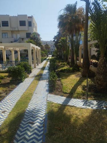 a walkway in front of a building with palm trees at Appartement complexe Arrous Bahr mikki beach vue piscine et jardin in Tangier