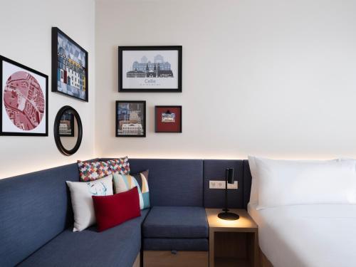 a room with a blue couch and pictures on the wall at Hampton By Hilton Celle in Celle