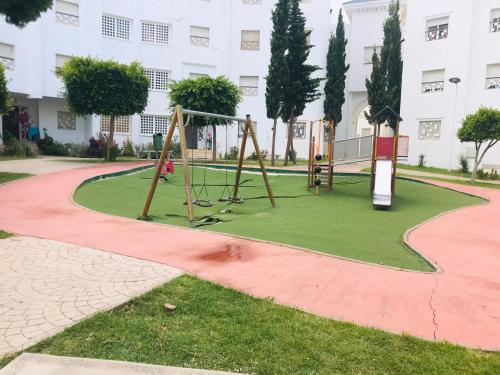 a playground in a park in front of a building at Appartement cosy in Fnidek