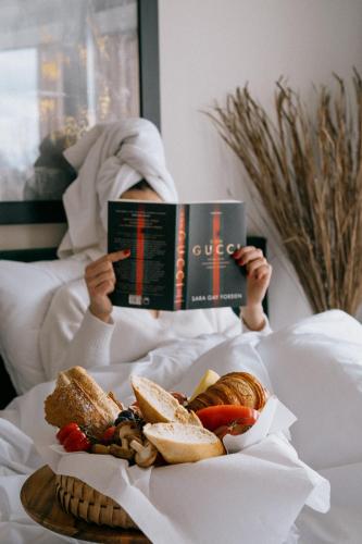 una persona che legge un libro a letto con un piatto di cibo di Laguna Beskidów Resort - Apartament A15 a Zarzecze