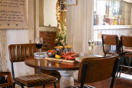 a table with a plate of food and two glasses of wine at The Windmill in Maidstone