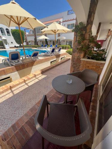 a patio with a table and chairs next to a pool at Camel Dive Club & Hotel - Boutique Hotel in Sharm El Sheikh