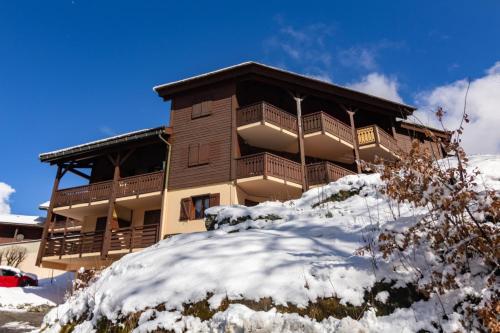 un grand bâtiment sur une colline enneigée dans l'établissement Appartement les Dryades D92 Happy Rentals, à Les Chavants