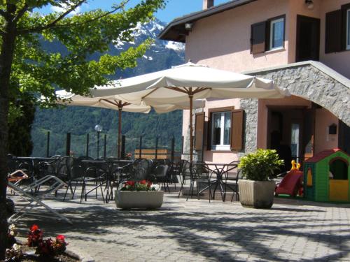 a patio with tables and chairs and umbrellas at Hotel Ristorante Miravalle in Teglio