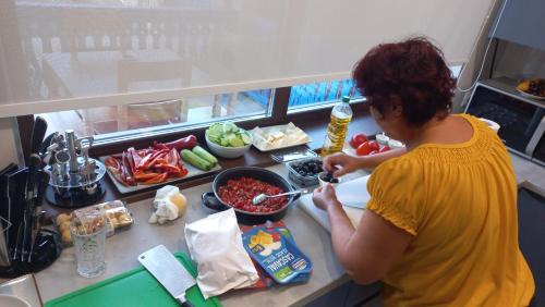 Una donna sta preparando il cibo in una cucina di Pensiunea Alicia a Jurilovca