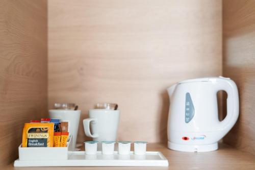 a white coffee maker sitting on a shelf with cups at Holiday Inn Hemel Hempstead M1, Jct. 8, an IHG Hotel in Hemel Hempstead