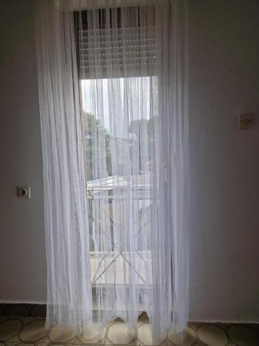 a window with white curtains in a room at Apartment Laura in Tisno