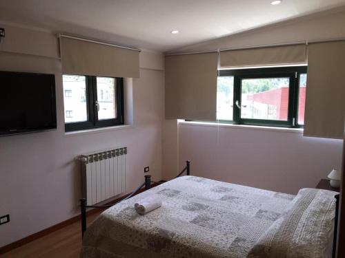 a bedroom with a bed and two windows at B&B Culla Dell'Aquila in LʼAquila
