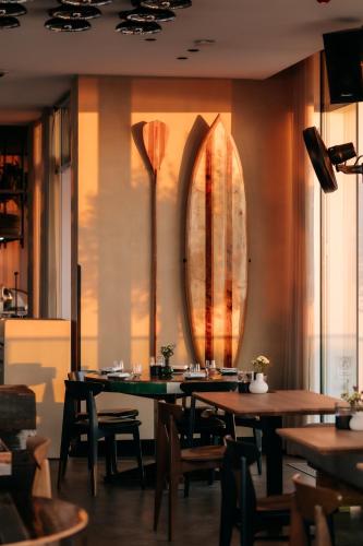 a dining room with tables and a surfboard on the wall at Strandhotel in Cadzand-Bad