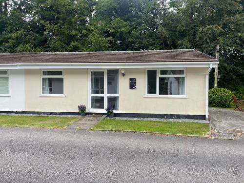 a small white house with a driveway at Beekeepers Cottage in Liskeard