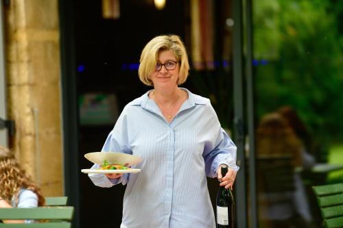 a woman holding a plate of food and a wine bottle at Le Mas Des Aigras - Hôtel & Restaurant de Charme en Provence in Orange