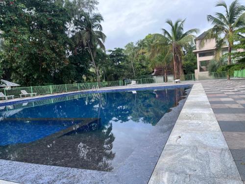 a swimming pool with blue water and palm trees at UVA Sands Beach Resort in Kundapur