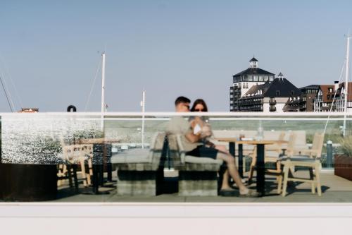 a man and woman sitting next to each other at a table at Strandhotel in Cadzand-Bad
