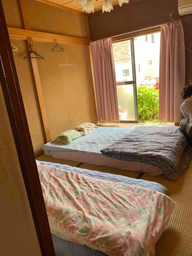two beds in a room with a window at Mason 2 ,direct to Disney,Narita AP, Haneda AP,Asakusa,Sky Tree Tower, Ueno Ueno in Kamagaya