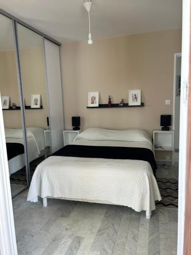 une chambre avec deux lits et un grand miroir dans l'établissement Lumière, à La Ciotat