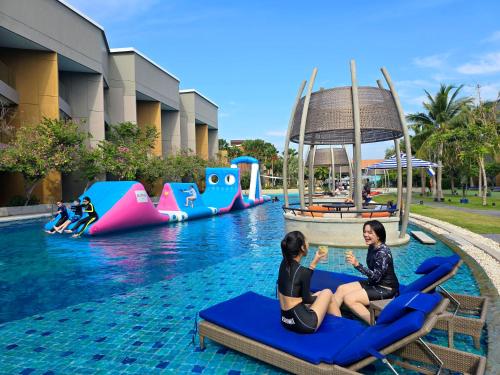 two women sitting on chairs in a pool at a resort at Avani+ Hua Hin Resort in Cha Am