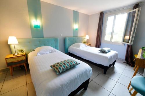 a hotel room with two beds and a window at Le Mas Des Aigras - Hôtel & Restaurant de Charme en Provence in Orange