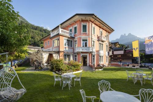 a large house with tables and chairs in the yard at Hotel Luis in Fiera di Primiero