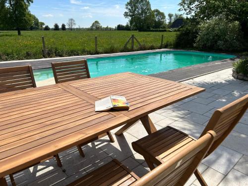 une table de pique-nique en bois et des chaises à côté d'une piscine dans l'établissement Maison de campagne en Normandie, à Saint-Martin-Saint-Firmin