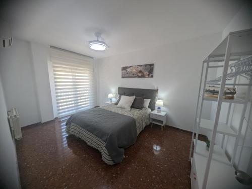a white bedroom with a bed and a window at Piso Céntrico Armilla in Armilla