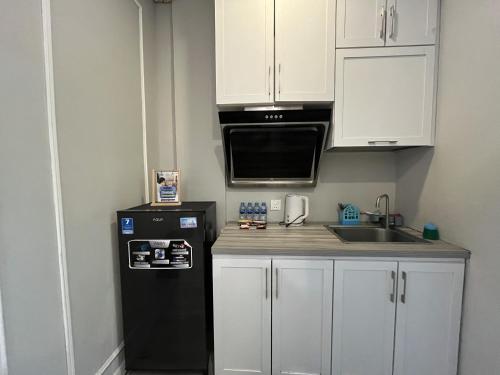 a kitchen with a black refrigerator and a sink at Casanova Penuin Batam in Nagoya
