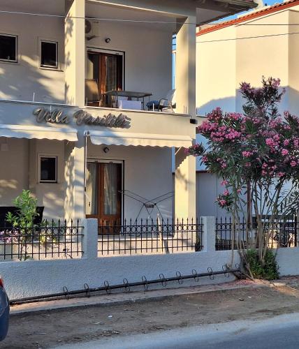 a white building with a fence and a tree at Villa Vasiliki in Skala Potamias