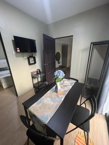 a dining room table with a vase of flowers on it at TC Maya Abaya Hotel in Kuantan