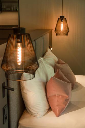 a bedroom with a bed with pillows and two lamps at Belia Lofts - ADULTS ONLY - Apartments in Appiano sulla Strada del Vino