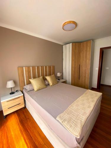a bedroom with a large bed with a wooden headboard at Apartamento nuevo en Zona Baja de Cotolino in Castro-Urdiales