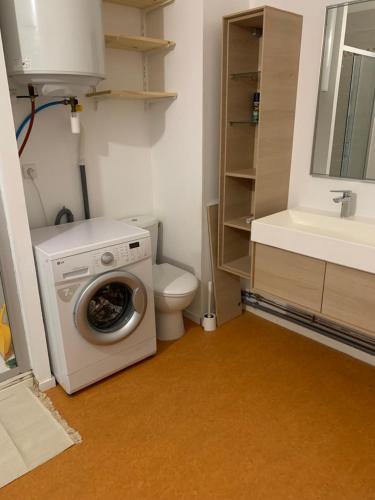une salle de bain avec machine à laver et toilettes dans l'établissement Appartement à Alençon, à Aleçon