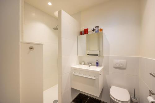 a white bathroom with a toilet and a sink at Het Zoute Zand - Parkeerplaats - Wifi - Comfort - Uitzonderlijke Locatie - Ideaal voor Stellen en Gezinnen in Knokke-Heist