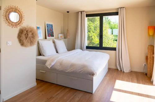 a bedroom with a large white bed and a window at Maison familiale avec piscine in Aix-en-Provence