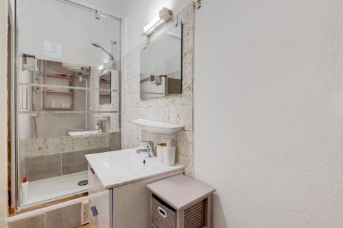 une salle de bain blanche avec un lavabo et un miroir dans l'établissement Brique du Capitole - Hypercentre, à Toulouse