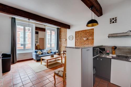 une cuisine et un salon avec un canapé dans l'établissement Brique du Capitole - Hypercentre, à Toulouse