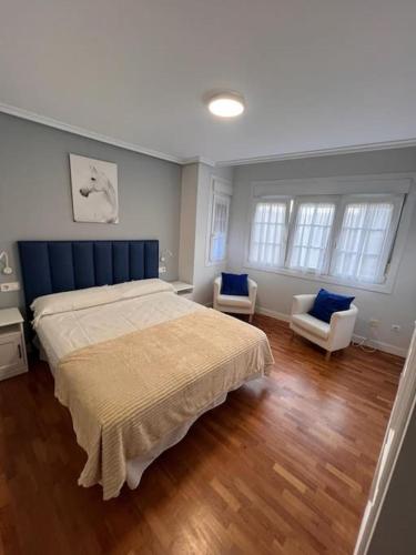 a bedroom with a large bed and two chairs at Villa Marie in Betanzos