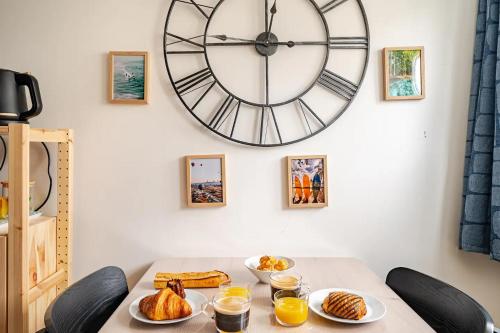 une table avec des assiettes de nourriture et une grande horloge dans l'établissement Tropical & cosy - Vieux Tours, à Tours