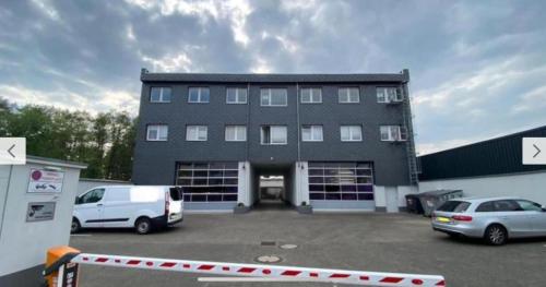 duży budynek z dwoma samochodami zaparkowanymi na parkingu w obiekcie Frühling Apartment w mieście Bergisch Gladbach