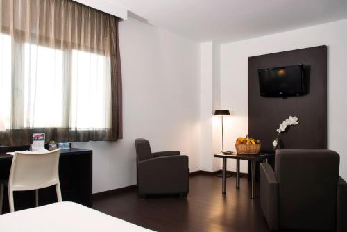 a hotel room with a table and chairs and a television at Hotel Sercotel Plana Parc in Alquerías del Niño Perdido